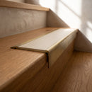 BN71SLR solid brass stair nosing in Antique Brass finish with Porth Stone Smooth Textured insert, fitted to a step edge