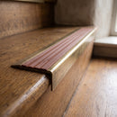 BN71SLR solid brass stair nosing in Antique Brass finish with Rustic Castellated insert, fitted to a step edge