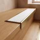 BN71SLR solid brass stair nosing in Antique Brass finish with White Castellated insert, fitted to a step edge