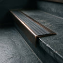 BN71SLR solid brass stair nosing in Antique Bronze finish with Black Castellated insert, fitted to a step edge