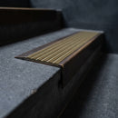 BN71SLR solid brass stair nosing in Antique Bronze finish with Olive Castellated insert, fitted to a step edge