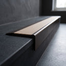BN71SLR solid brass stair nosing in Antique Bronze finish with Porth Stone Castellated insert, fitted to a step edge