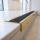 BN71SLR solid brass stair nosing in Polished Brass finish with Black Olympic Grip insert, fitted to a step edge