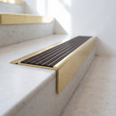 BN71SLR solid brass stair nosing in Polished Brass finish with Peat Castellated insert, fitted to a step edge