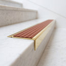 BN71SLR solid brass stair nosing in Polished Brass finish with Rustic Castellated insert, fitted to a step edge