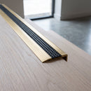 BN71SLR solid brass stair nosing in Satin Brass finish with Black Olympic Grip insert, fitted to a step edge