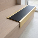 BN71SLR solid brass stair nosing in Satin Brass finish with Black Smooth Textured insert, fitted to a step edge