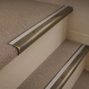 Antique Brass finish with Light Grey Castellated insert - 63.5mm solid brass bullnose stair nosing fitted to a carpeted step