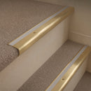 Satin Brass finish with Light Grey Castellated insert - 63.5mm solid brass bullnose stair nosing fitted to a carpeted step
