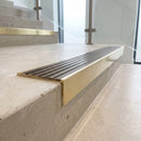 Solid brass 59mm slimline stair nosing with Antique Bronze anti-slip insert fitted to a concrete step in a commercial stairwell