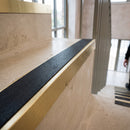 Solid brass 59mm slimline stair nosing with Black Smooth Textured anti-slip insert fitted to a concrete step in a commercial stairwell