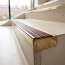 Solid brass 59mm slimline stair nosing with Claret Castellated anti-slip insert fitted to a concrete step in a commercial stairwell
