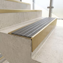 Solid brass 59mm slimline stair nosing with Flint Castellated anti-slip insert fitted to a concrete step in a commercial stairwell