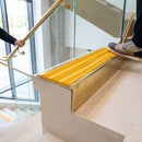 Solid brass 59mm slimline stair nosing with Gold Castellated anti-slip insert fitted to a concrete step in a commercial stairwell