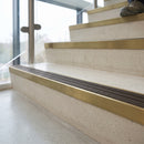 Solid brass 59mm slimline stair nosing with Granite Castellated anti-slip insert fitted to a concrete step in a commercial stairwell