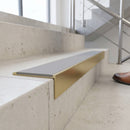Solid brass 59mm slimline stair nosing with Light Grey Smooth Textured anti-slip insert fitted to a concrete step in a commercial stairwell
