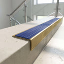 Solid brass 59mm slimline stair nosing with Mid Blue Castellated anti-slip insert fitted to a concrete step in a commercial stairwell