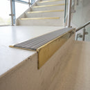 Solid brass 59mm slimline stair nosing with Nimbus Castellated anti-slip insert fitted to a concrete step in a commercial stairwell