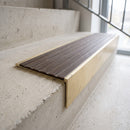 Solid brass 59mm slimline stair nosing with Olive Castellated anti-slip insert fitted to a concrete step in a commercial stairwell
