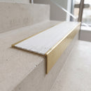 Solid brass 59mm slimline stair nosing with Polar Grey Castellated anti-slip insert fitted to a concrete step in a commercial stairwell