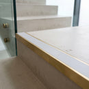 Solid brass 59mm slimline stair nosing with Polar Grey Smooth Textured anti-slip insert fitted to a concrete step in a commercial stairwell