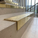 Solid brass 59mm slimline stair nosing with Polished Brass anti-slip insert fitted to a concrete step in a commercial stairwell