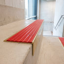 Solid brass 59mm slimline stair nosing with Poppy Castellated anti-slip insert fitted to a concrete step in a commercial stairwell