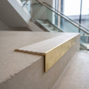 Solid brass 59mm slimline stair nosing with Porth Stone Castellated anti-slip insert fitted to a concrete step in a commercial stairwell