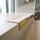 Solid brass 59mm slimline stair nosing with Porth Stone Smooth Textured anti-slip insert fitted to a concrete step in a commercial stairwell
