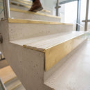 Solid brass 59mm slimline stair nosing with Satin Brass anti-slip insert fitted to a concrete step in a commercial stairwell