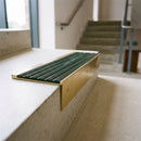 Solid brass 59mm slimline stair nosing with Spruce Castellated anti-slip insert fitted to a concrete step in a commercial stairwell