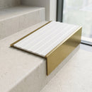 Solid brass 59mm slimline stair nosing with White Castellated anti-slip insert fitted to a concrete step in a commercial stairwell