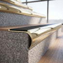 Solid brass bullnose stair nosing in Polished Brass finish with black castellated anti-slip infill fitted to a stair tread in a commercial stairwell