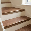 Bronze anodised stair nosing fitted to walnut LVT steps, the vinyl butting the smooth rounded bead with a shallow ribbed band down the top of the riser