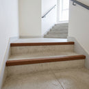 Brown GRP anti-slip stair nosings fitted to the front edge of concrete steps in a stairwell