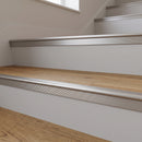 Brushed silver anodised stair nosing with a fine directional grain fitted to warm oak LVT steps in an office reception