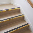 Bullnose aluminium stair nosing with a dark charcoal Mor Grip insert in mirrorflect gold finish fitted on a flat or apartment communal stair finished in beige vinyl