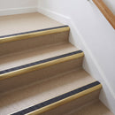 Bullnose aluminium stair nosing with a dark charcoal Mor Grip insert in satin gold finish fitted on a flat or apartment communal stair finished in beige vinyl