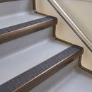 Bullnose aluminium stair nosing with a dark charcoal Mor Grip insert in dark bronze finish fitted on a hotel or office stair finished in light grey vinyl