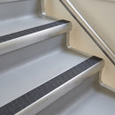 Bullnose aluminium stair nosing with a dark charcoal Mor Grip insert in mill finish finish fitted on a hotel or office stair finished in light grey vinyl