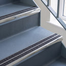 Bullnose aluminium stair nosing with twin dark charcoal Mor Grip inserts in bright polished finish fitted on a hospital or clinic stair finished in blue-grey safety vinyl