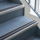 Bullnose aluminium stair nosing with twin dark charcoal Mor Grip inserts in mill finish finish fitted on a hospital or clinic stair finished in blue-grey safety vinyl