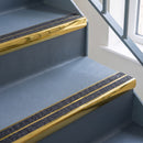 Bullnose aluminium stair nosing with twin dark charcoal Mor Grip inserts in mirrorflect gold finish fitted on a hospital or clinic stair finished in blue-grey safety vinyl