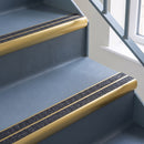 Bullnose aluminium stair nosing with twin dark charcoal Mor Grip inserts in satin gold finish fitted on a hospital or clinic stair finished in blue-grey safety vinyl