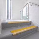 Bullnose DDA aluminium stair nosing 70 x 56mm in Satin Gold with Brimstone Exterior Grip insert, fitted to grey vinyl stairs in an office stairwell