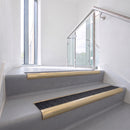 Bullnose DDA aluminium stair nosing 70 x 56mm in Satin Gold with Coal Exterior Grip insert, fitted to grey vinyl stairs in an office stairwell