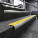 Bullnose stair nosing with high-visibility yellow anti-slip insert on dark concrete industrial steps