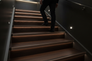 uPVC wood effect stair nosing in Dark Walnut — real-life installation on UK staircase with person using the stairs
