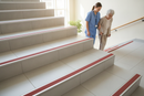Anti-slip bullnose stair nosing with Red insert — installed on UK staircase, semi-rounded profile with person using stairs