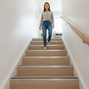 46mm aluminium stair nosing with black rubber insert installed on oak laminate UK home staircase - woman descending safely